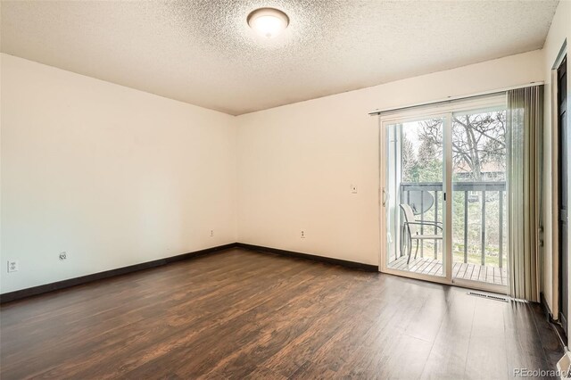 empty room featuring baseboards, a textured ceiling, dark wood-style floors, and visible vents