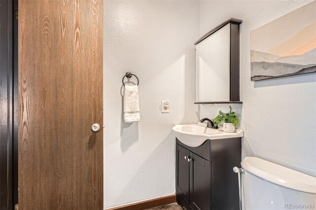 bathroom with vanity, baseboards, and toilet