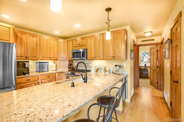 2891 Nugget Rd, Fairplay, CO 80440 - kitchen with stainless steel appliances, a breakfast bar area, light stone counters, decorative light fixtures, and recessed lighting