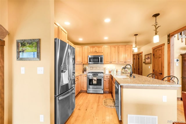 2891 Nugget Rd, Fairplay, CO 80440 - kitchen with stainless steel appliances, a sink, light brown cabinets, a peninsula, and light wood-style flooring