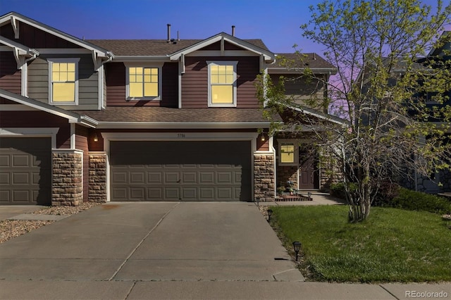 view of front of home with stone siding, driveway, an attached garage, and a shingled roof