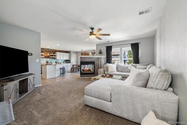 living area featuring ceiling fan, light carpet, and a multi sided fireplace