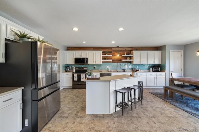 kitchen featuring appliances with stainless steel finishes, a sink, open shelves, white cabinets, and tasteful backsplash