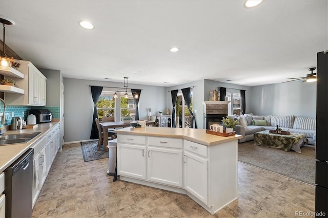 kitchen featuring dishwasher, a sink, a kitchen island, light countertops, and recessed lighting
