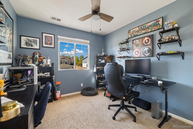 carpeted office space featuring ceiling fan and baseboards