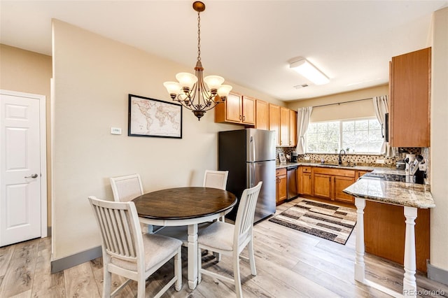 dining space with sink, light wood-type flooring, and a notable chandelier