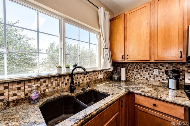 kitchen with sink, stone countertops, and decorative backsplash