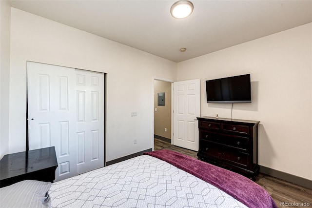 bedroom with dark wood-type flooring, electric panel, and a closet