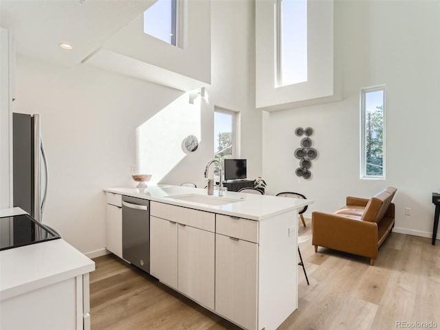 kitchen with kitchen peninsula, light hardwood / wood-style floors, sink, stainless steel dishwasher, and fridge