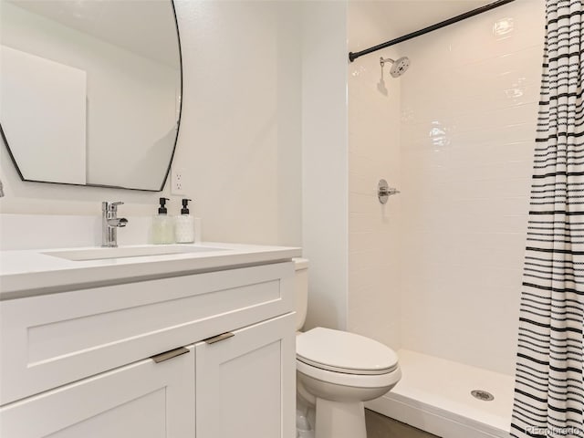 bathroom featuring vanity, tiled shower, and toilet