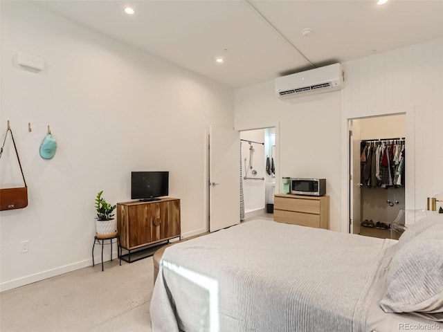 bedroom featuring ensuite bath, an AC wall unit, a walk in closet, and a closet