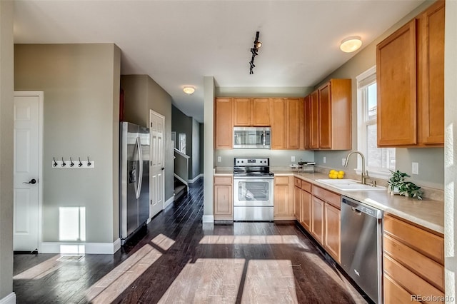 kitchen featuring sink, dark wood-type flooring, rail lighting, and appliances with stainless steel finishes