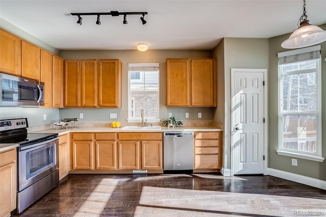 kitchen featuring appliances with stainless steel finishes, pendant lighting, sink, dark hardwood / wood-style flooring, and light brown cabinets