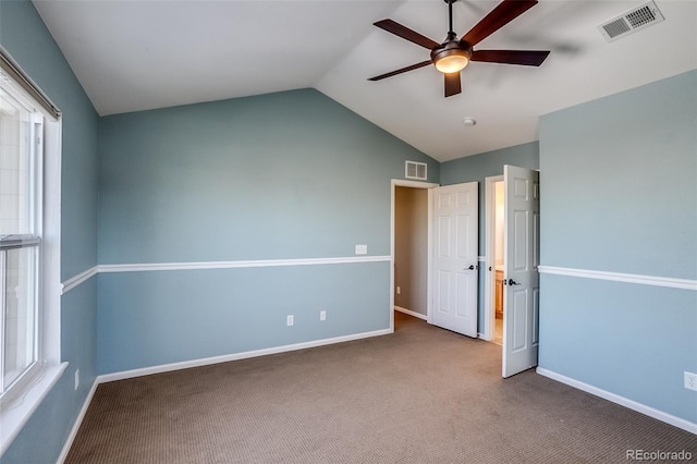 unfurnished bedroom featuring ceiling fan, lofted ceiling, carpet flooring, and multiple windows