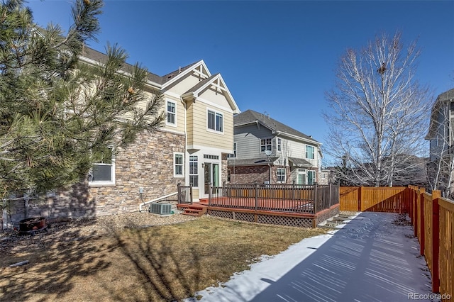 snow covered back of property with a wooden deck, a lawn, and cooling unit