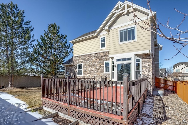 snow covered back of property with a deck