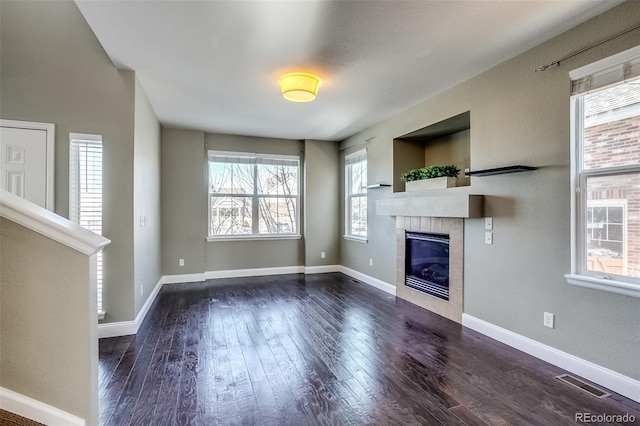 unfurnished living room with dark wood-type flooring and a tile fireplace