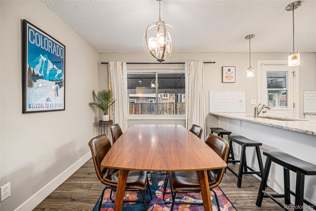7005 Zenobia Pl, Westminster, CO 80030 - dining room featuring a textured ceiling, an inviting chandelier, dark wood-style floors, and baseboards