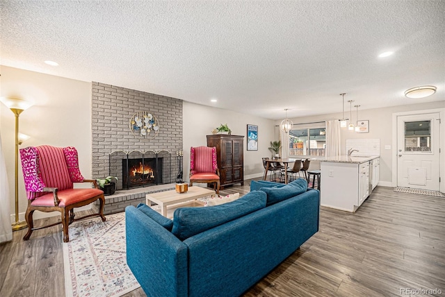7005 Zenobia Pl, Westminster, CO 80030 - living room with recessed lighting, a textured ceiling, a brick fireplace, and wood finished floors