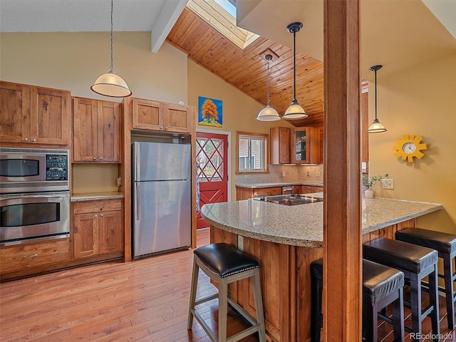 7585 Native Dancer Trl, Evergreen, CO 80439 - kitchen featuring stainless steel appliances, brown cabinetry, light wood-type flooring, a skylight, and a breakfast bar