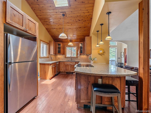 7585 Native Dancer Trl, Evergreen, CO 80439 - kitchen featuring stainless steel appliances, a peninsula, a sink, brown cabinetry, and lofted ceiling