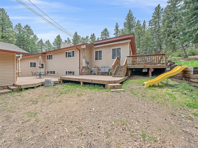 7585 Native Dancer Trl, Evergreen, CO 80439 - rear view of house with a chimney, a deck, and a playground