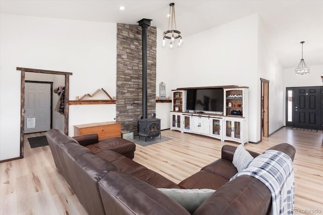 living room featuring a high ceiling, a wood stove, and light wood-type flooring