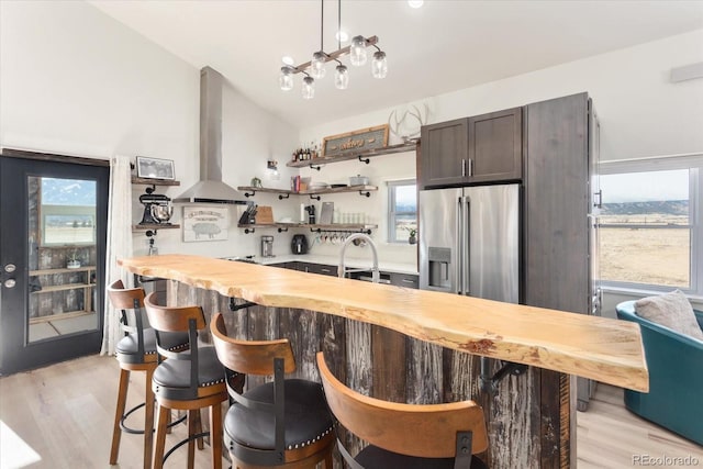 kitchen with pendant lighting, butcher block countertops, lofted ceiling, high end refrigerator, and exhaust hood