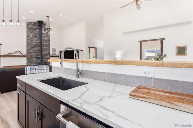 kitchen featuring sink, ceiling fan, light stone counters, decorative light fixtures, and vaulted ceiling