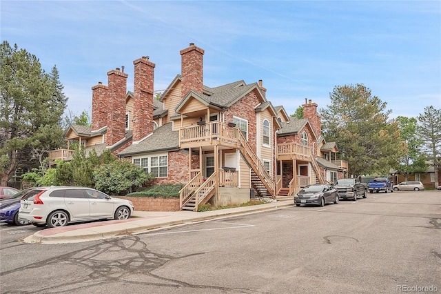 view of front facade with a chimney, stairs, and brick siding