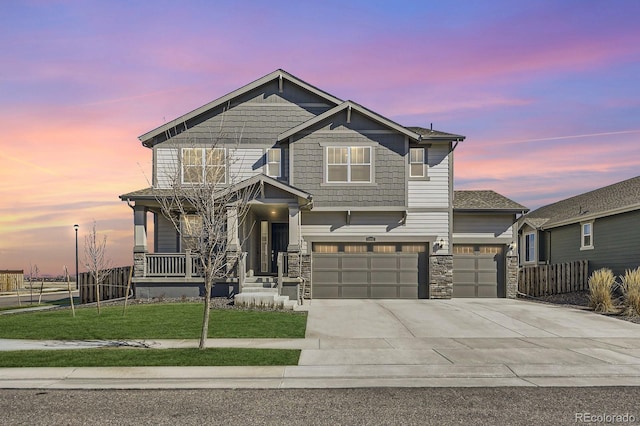 view of front of property with an attached garage, covered porch, driveway, stone siding, and a front lawn