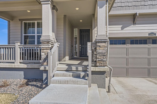 view of exterior entry featuring a garage, covered porch, and stone siding