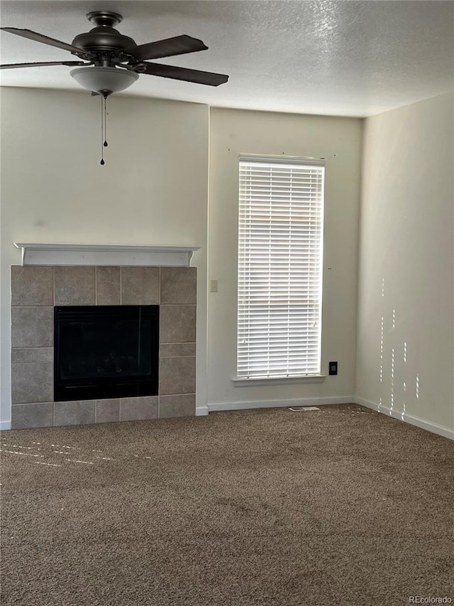 unfurnished living room featuring a textured ceiling, a tiled fireplace, carpet floors, and ceiling fan