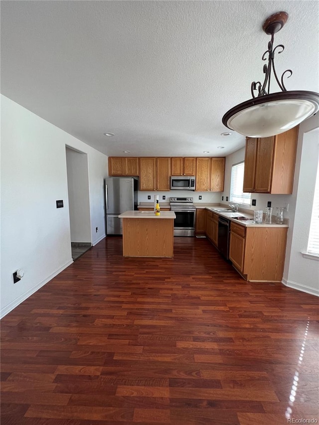 kitchen with appliances with stainless steel finishes, dark hardwood / wood-style floors, sink, decorative light fixtures, and a center island