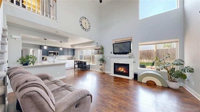 21570 E 40th Pl, Denver, CO 80249 - living room featuring a towering ceiling, plenty of natural light, a fireplace with flush hearth, and dark wood-style floors