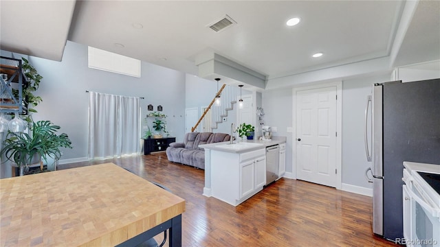 21570 E 40th Pl, Denver, CO 80249 - kitchen with stainless steel dishwasher, white range with electric stovetop, dark wood-type flooring, a peninsula, and white cabinets