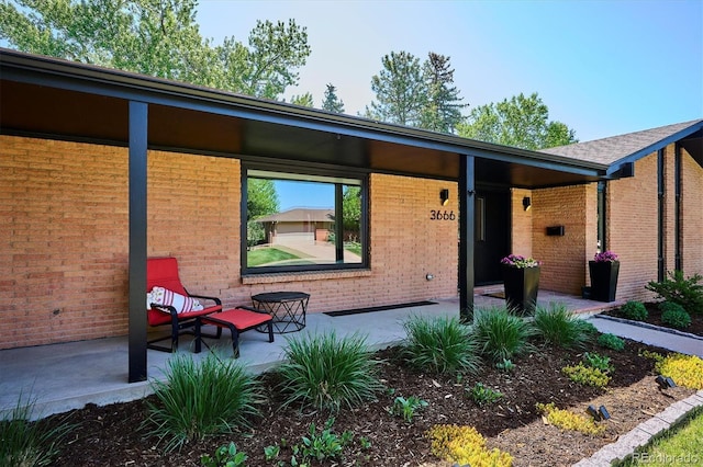 view of exterior entry with brick siding and a patio area