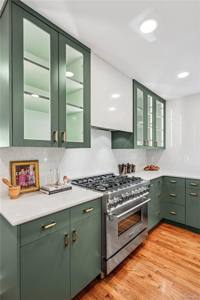 kitchen featuring high end stove, green cabinetry, and recessed lighting