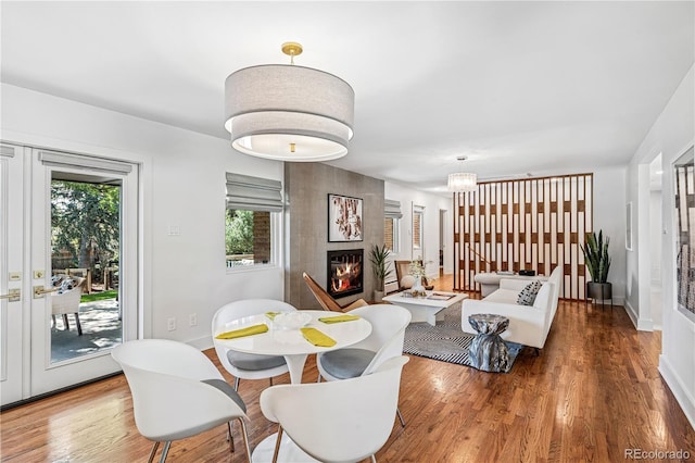 dining room with a fireplace, wood finished floors, and baseboards