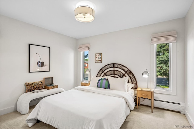 bedroom featuring a baseboard heating unit, multiple windows, and light carpet