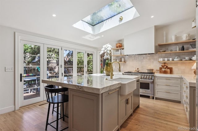 435 Ivanhoe St, Denver, CO 80220 - kitchen with open shelves, a skylight, stainless steel appliances, backsplash, and light stone countertops