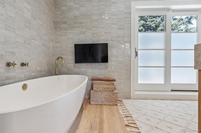 435 Ivanhoe St, Denver, CO 80220 - bathroom featuring a freestanding tub, wood finished floors, and tile walls