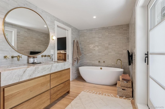 435 Ivanhoe St, Denver, CO 80220 - full bath featuring tile walls, vanity, a freestanding bath, and wood finished floors