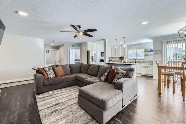 living area with dark wood-type flooring, recessed lighting, a textured ceiling, and baseboards