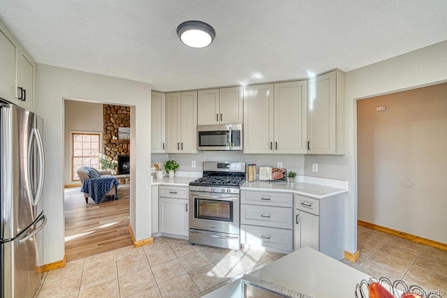 318 Southgate Rd, Florissant, CO 80816 - kitchen with stainless steel appliances, light countertops, baseboards, a fireplace, and light tile patterned floors