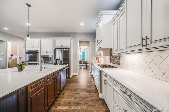 2362 Spruce Way, Denver, CO 80238 - kitchen featuring arched walkways, a sink, appliances with stainless steel finishes, white cabinetry, and tasteful backsplash