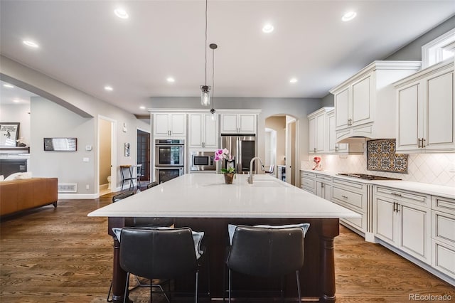 2362 Spruce Way, Denver, CO 80238 - kitchen featuring arched walkways, a sink, appliances with stainless steel finishes, tasteful backsplash, and a kitchen bar