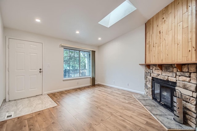 unfurnished living room featuring light wood-type flooring, a fireplace, visible vents, and a skylight