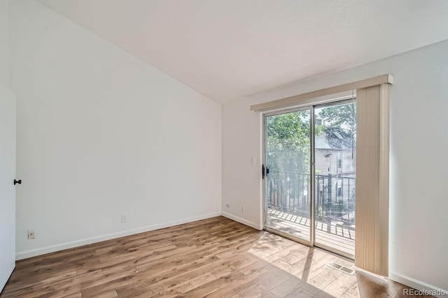 unfurnished room featuring visible vents, wood finished floors, baseboards, and lofted ceiling