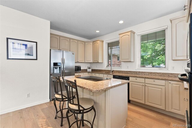 1901 S Union Pl, Lakewood, CO 80228 - kitchen featuring stainless steel appliances, a center island, light stone countertops, a kitchen bar, and light wood-style floors